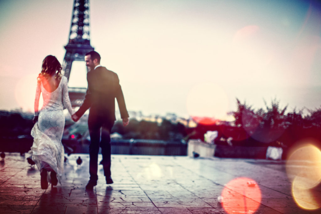 Young couple together in front of an Eiffel Tower in Paris, France - on their first day as married couple.